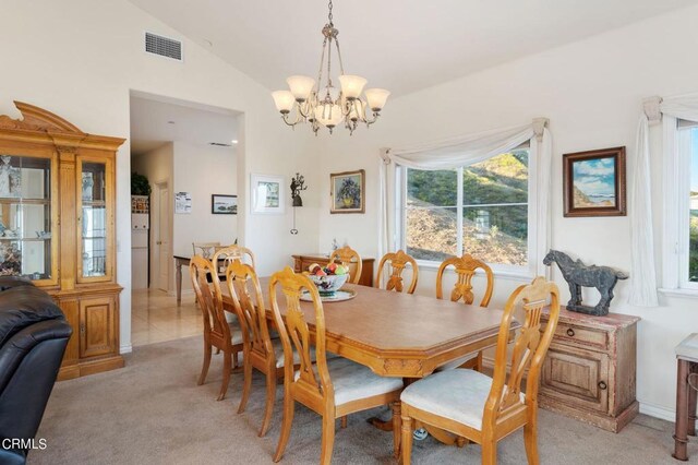 dining room featuring an inviting chandelier, vaulted ceiling, and light colored carpet