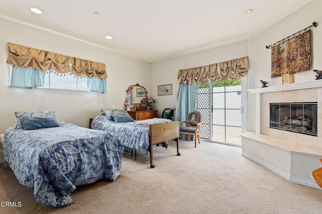 bedroom featuring carpet floors, a tiled fireplace, and access to outside