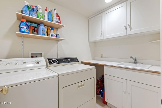 clothes washing area featuring sink, washer and clothes dryer, and cabinets