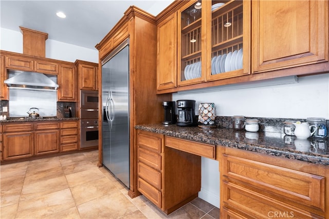 kitchen with built in appliances, light tile flooring, and dark stone countertops