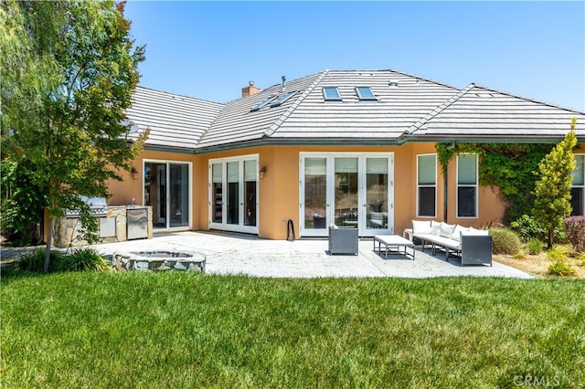 rear view of property with a lawn, an outdoor living space, and a patio