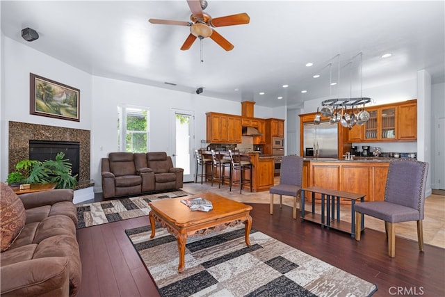 living room with ceiling fan, a high end fireplace, and hardwood / wood-style floors