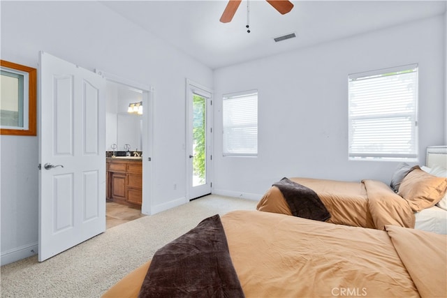 bedroom with access to outside, ceiling fan, multiple windows, light carpet, and connected bathroom