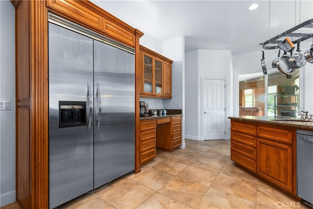 kitchen featuring stainless steel appliances, sink, dark stone counters, and light tile floors