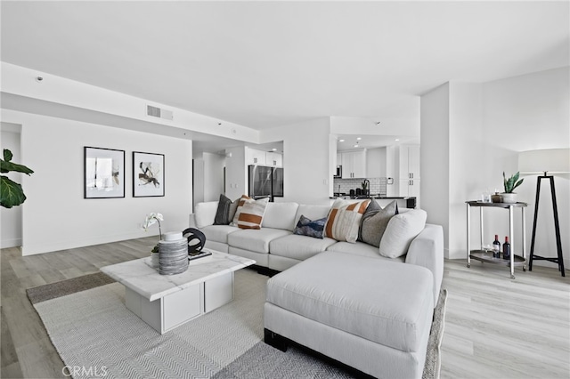 living room featuring sink and light hardwood / wood-style flooring