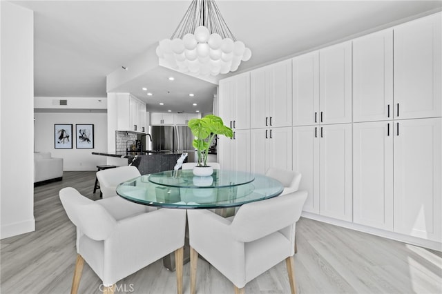 dining area with an inviting chandelier and light hardwood / wood-style flooring