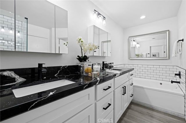 bathroom featuring vanity, wood-type flooring, and a tub