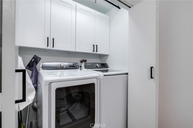 clothes washing area with cabinets and washer and dryer