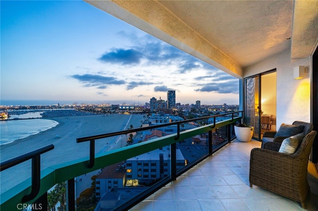 balcony at dusk featuring a water view