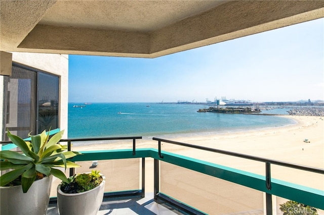 balcony with a water view and a view of the beach