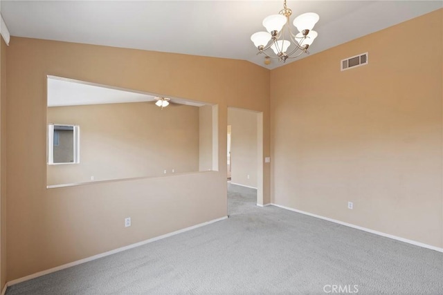 carpeted spare room with a notable chandelier and vaulted ceiling