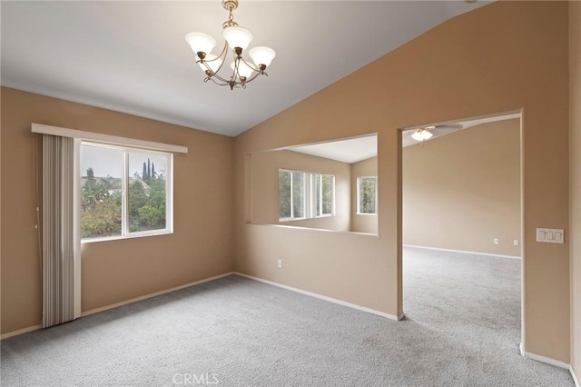 empty room with ceiling fan with notable chandelier, light colored carpet, and vaulted ceiling