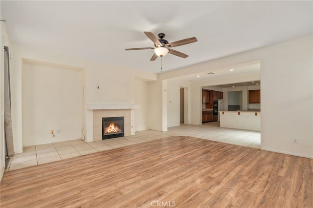 unfurnished living room featuring ceiling fan, a fireplace, and light wood-type flooring