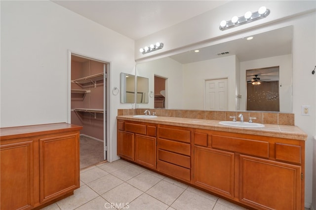 bathroom with tile flooring, oversized vanity, dual sinks, and ceiling fan