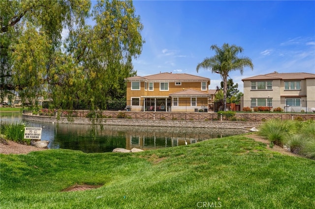 back of house featuring a lawn and a water view