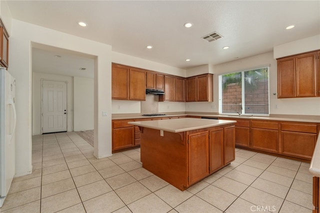 kitchen featuring a center island, stainless steel gas cooktop, light tile flooring, and white fridge