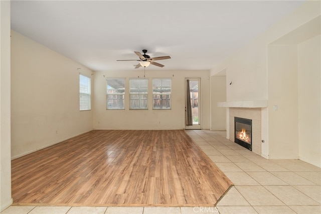 unfurnished living room featuring a tile fireplace, ceiling fan, and light hardwood / wood-style flooring