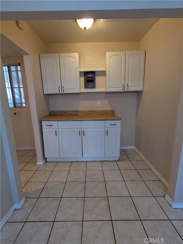 kitchen featuring white cabinets, light tile patterned flooring, and butcher block countertops