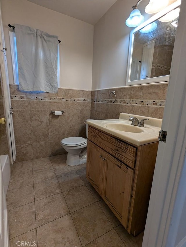 bathroom featuring tile patterned flooring, vanity, toilet, and tile walls