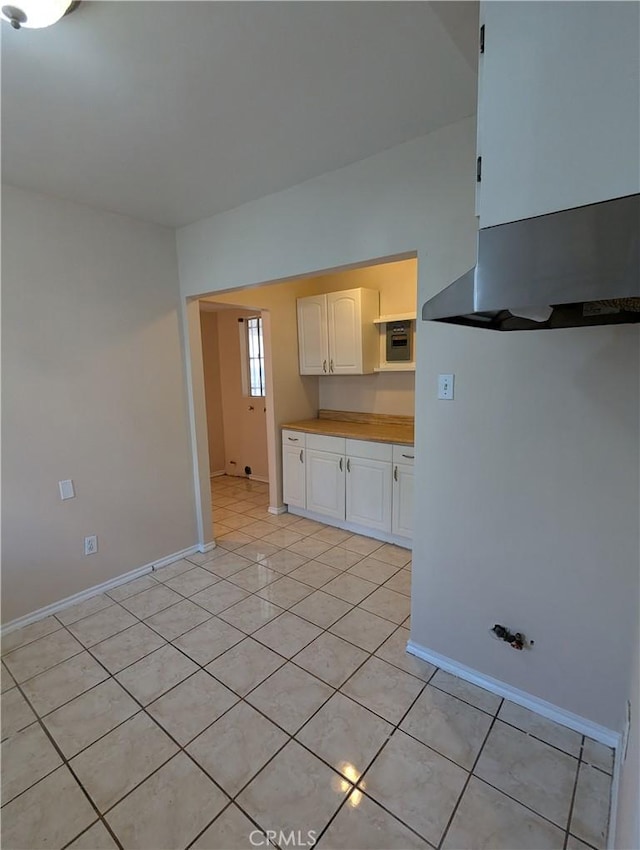 kitchen featuring white cabinets, light tile patterned flooring, and range hood