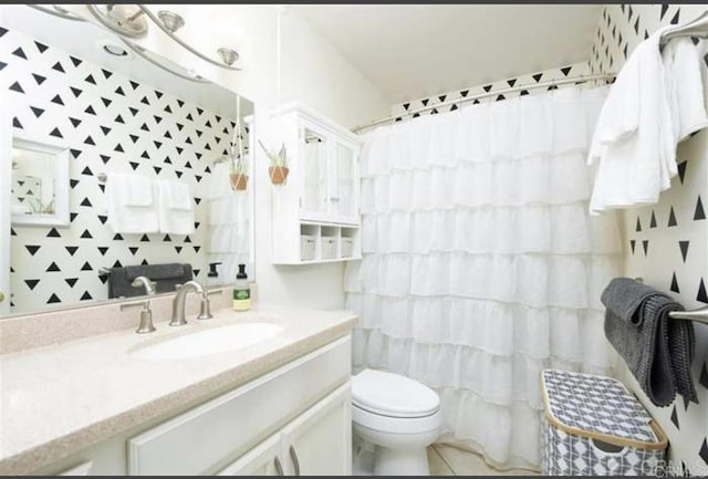 bathroom with tile patterned floors, vanity, toilet, and curtained shower