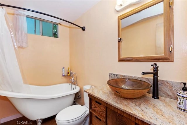 bathroom featuring vanity, a tub to relax in, and toilet