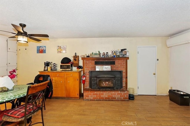 kitchen featuring ceiling fan, light hardwood / wood-style flooring, a wall unit AC, a textured ceiling, and a fireplace