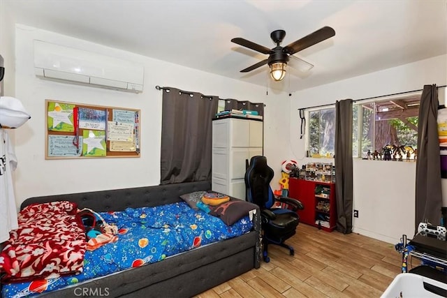 bedroom featuring ceiling fan, a wall unit AC, and light hardwood / wood-style flooring