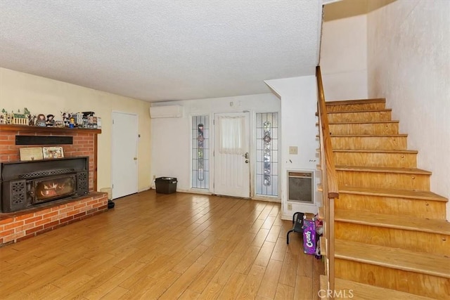 interior space with a fireplace, wood-type flooring, a textured ceiling, and heating unit