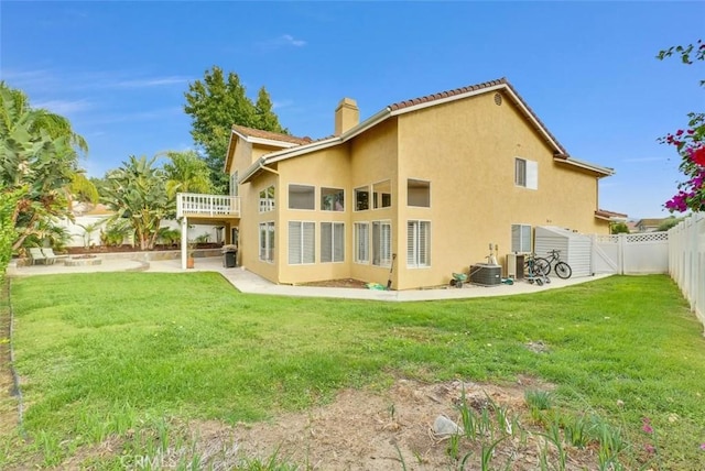 rear view of house featuring a patio area, central AC, and a yard