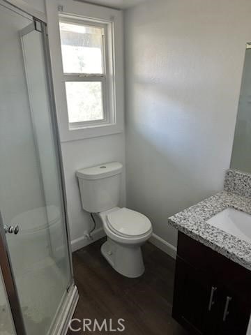 bathroom with a shower with door, vanity, hardwood / wood-style floors, and toilet