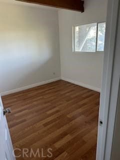 unfurnished room with beamed ceiling and dark hardwood / wood-style flooring