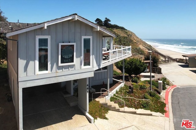 view of side of home featuring a water view, a balcony, a beach view, and a carport