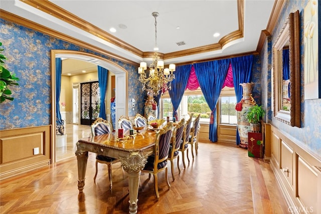 dining area with an inviting chandelier, crown molding, light parquet flooring, and a tray ceiling