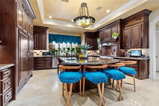 kitchen featuring backsplash, a raised ceiling, decorative light fixtures, and stainless steel appliances