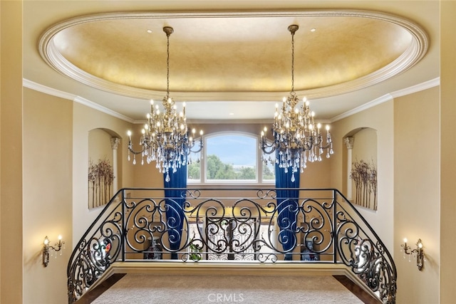 staircase with a raised ceiling, ornamental molding, and a chandelier