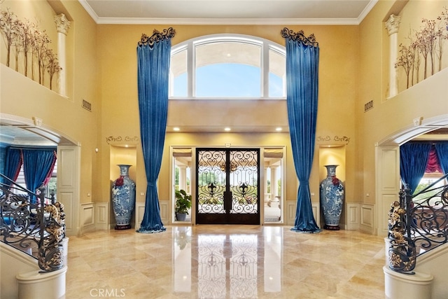 foyer featuring a towering ceiling, french doors, and a healthy amount of sunlight