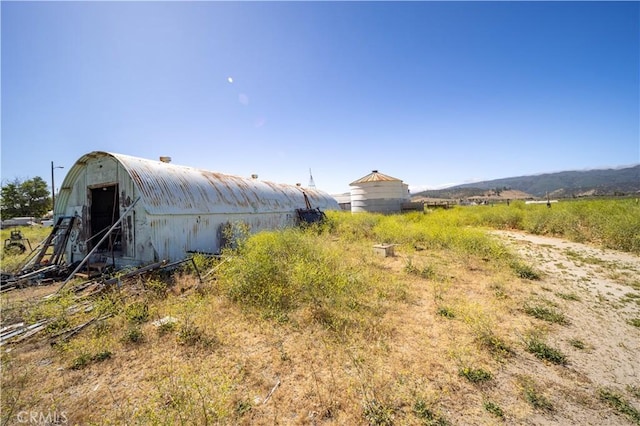 view of yard featuring a mountain view, a rural view, and an outdoor structure