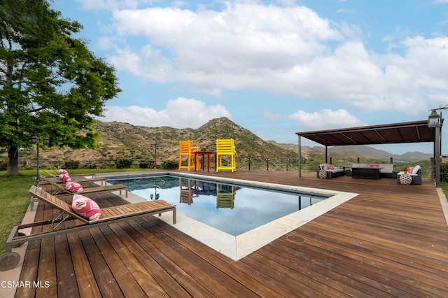 view of pool with outdoor lounge area and a deck with mountain view