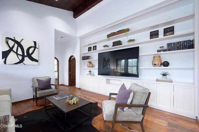 living room with wooden ceiling, a high ceiling, hardwood / wood-style floors, and built in shelves