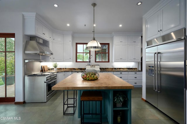 kitchen featuring high quality appliances, wood counters, ornamental molding, a center island, and white cabinets