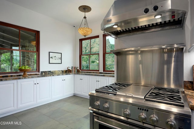 kitchen with hanging light fixtures, dark stone counters, ventilation hood, white cabinets, and stainless steel range oven