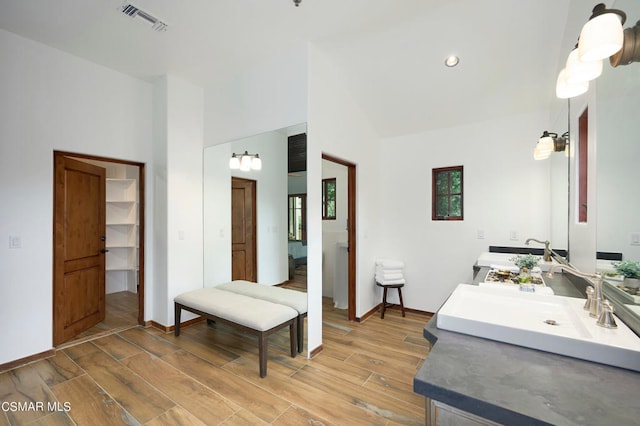 bathroom with vanity, hardwood / wood-style flooring, and high vaulted ceiling