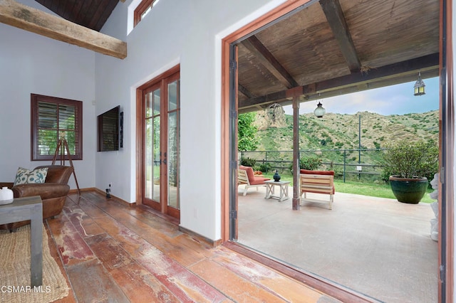 doorway with vaulted ceiling with beams, french doors, wood ceiling, a mountain view, and hardwood / wood-style flooring