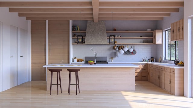 kitchen with backsplash, beamed ceiling, light hardwood / wood-style flooring, and a kitchen bar