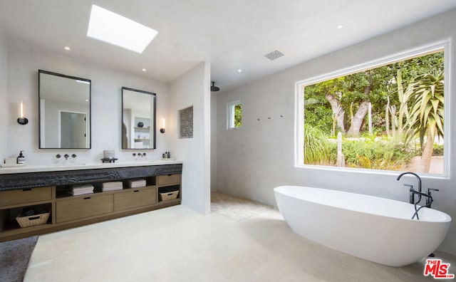 bathroom featuring vanity, a tub to relax in, and a skylight