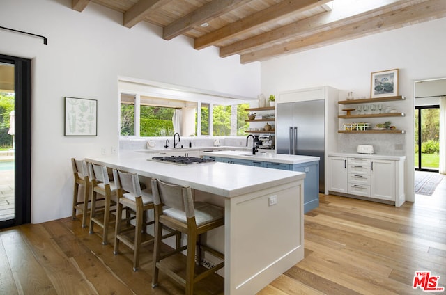 kitchen featuring beamed ceiling, white cabinetry, a kitchen breakfast bar, light hardwood / wood-style floors, and kitchen peninsula