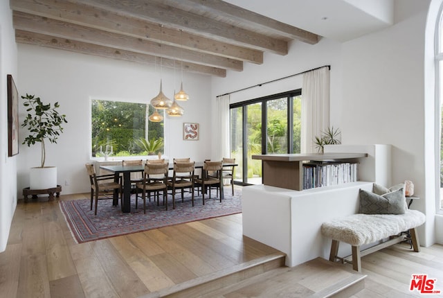 dining space featuring an inviting chandelier, beam ceiling, and light hardwood / wood-style floors