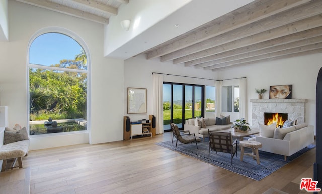 living room with a fireplace, light hardwood / wood-style floors, and beamed ceiling