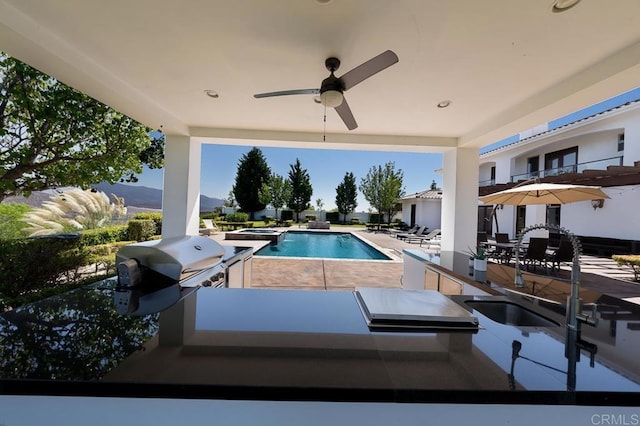 view of pool with a patio, a mountain view, a grill, and sink